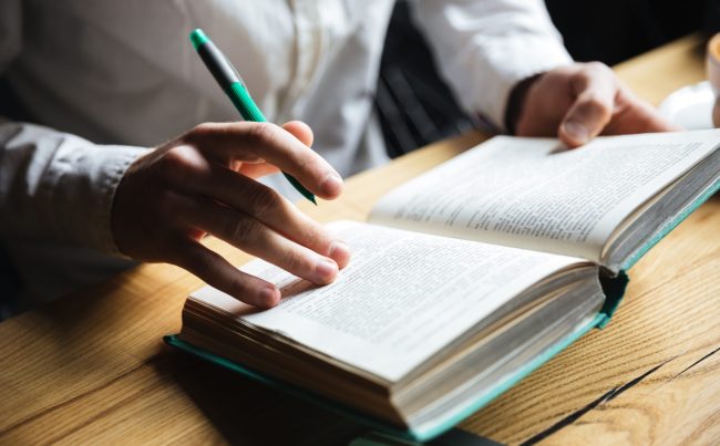 Cropped photo of man in white shirt reading book